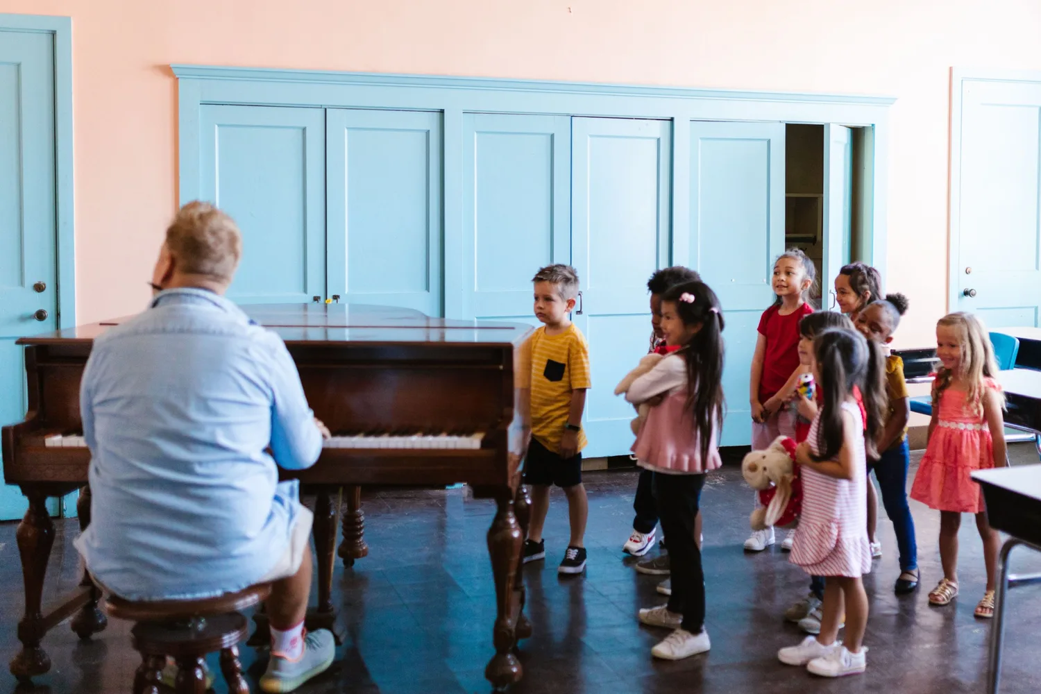 Des enfants attentifs autour d’un piano, pendant qu’un musicien joue