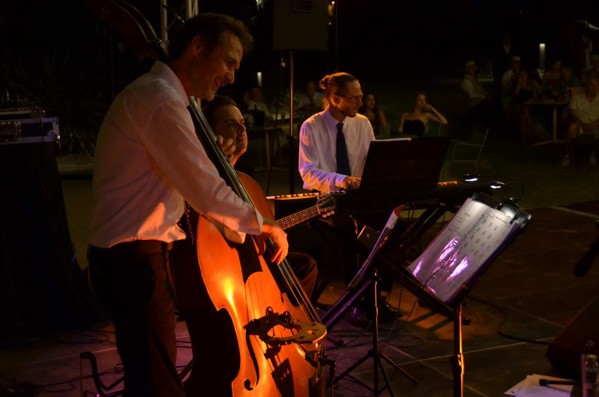 Le contrebassiste et le pianiste de l’orchestre en concert, dans une lumière orangée.