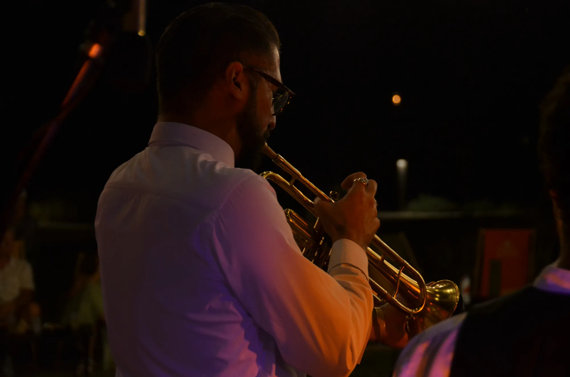 Un trompettiste de l’orchestre en plein solo, dans la nuit.