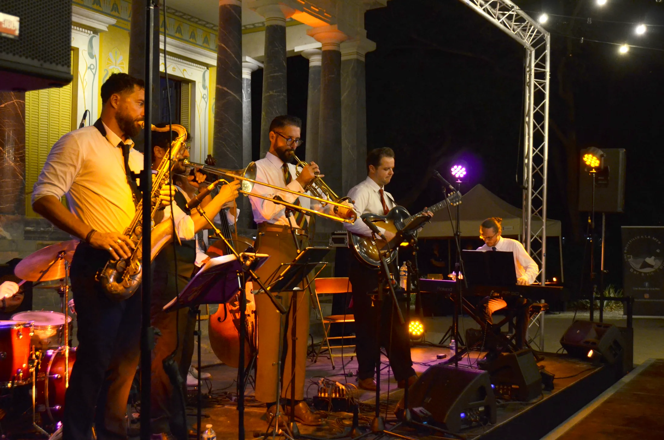 Le saxophone, la trompette et le trombone de l’orchestre, debout devant le château.