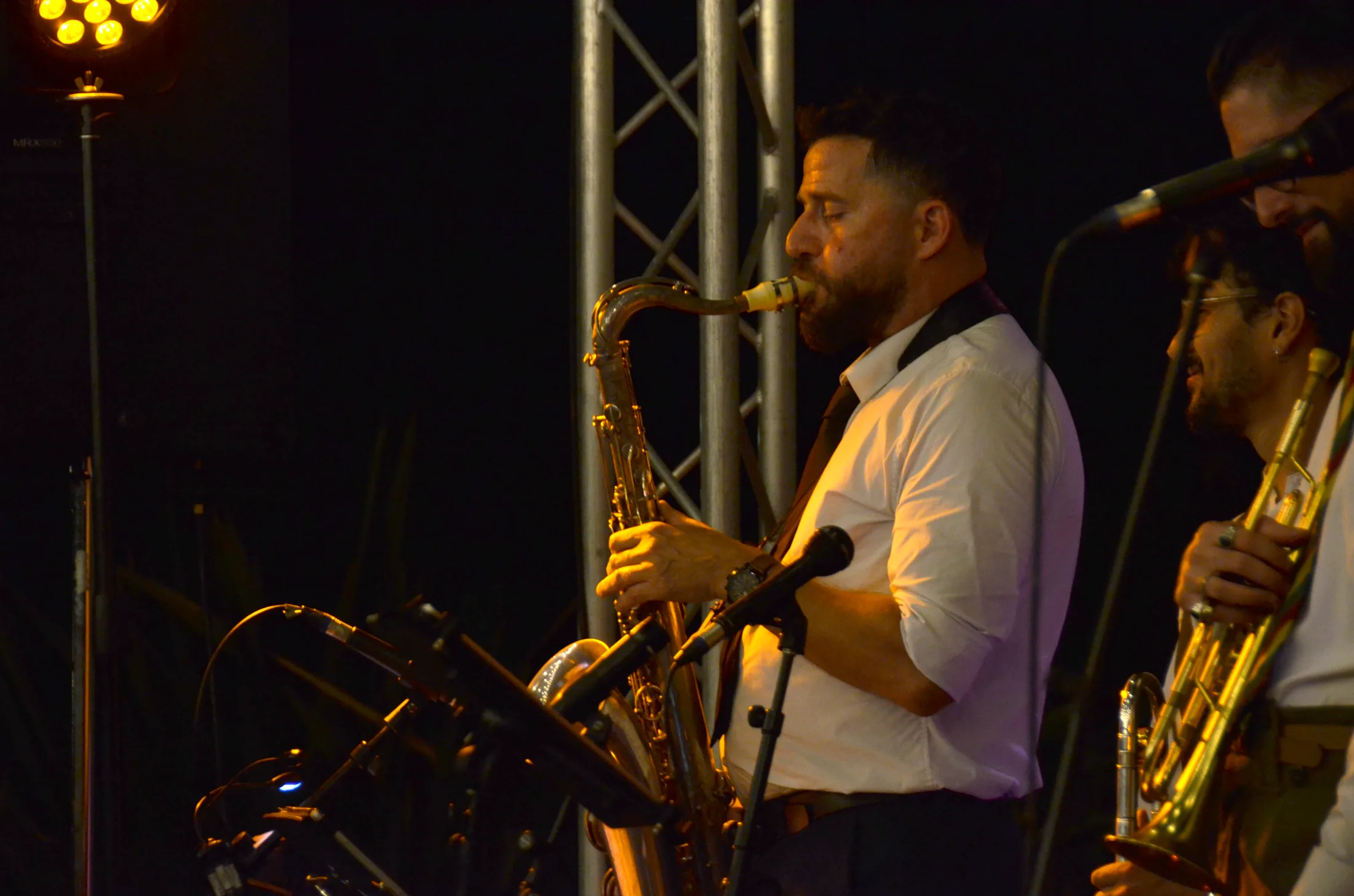 Un saxophoniste de l’orchestre sous un projecteur violet.