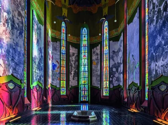 Une salle du Château Laurens éclairée par de hauts vitraux colorés.