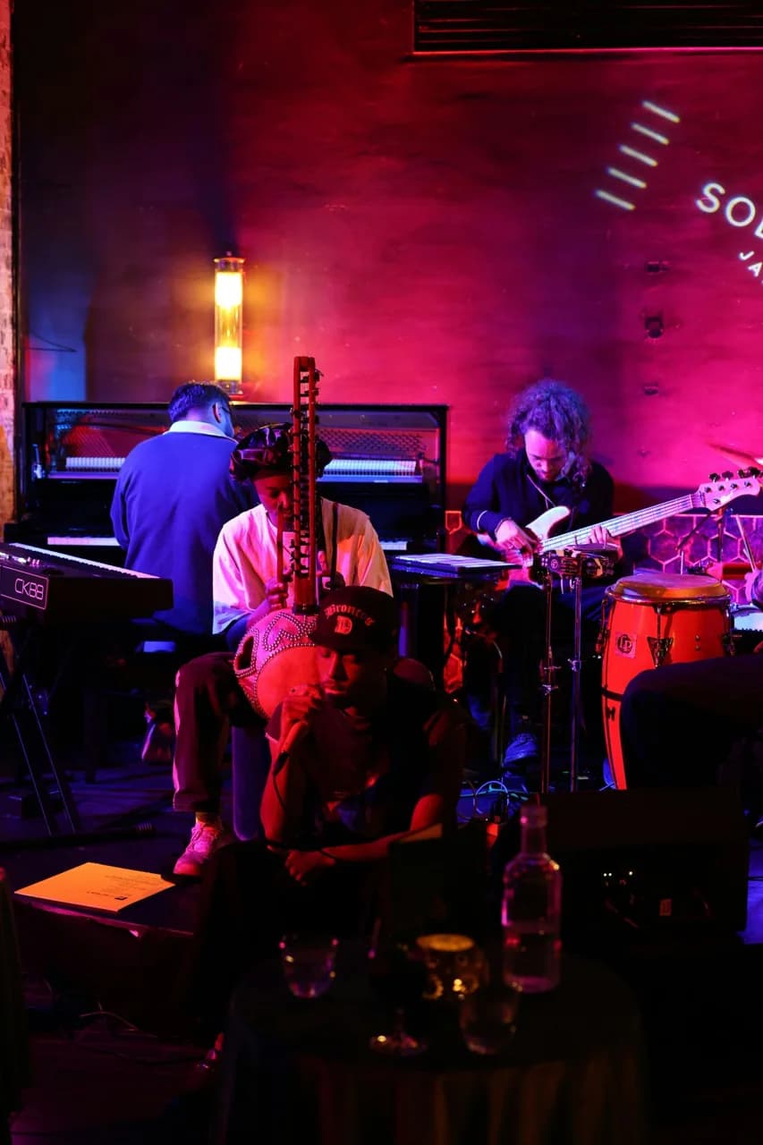 Une formation de jazz en concert dans un club baigné de lumières rouges et bleues.