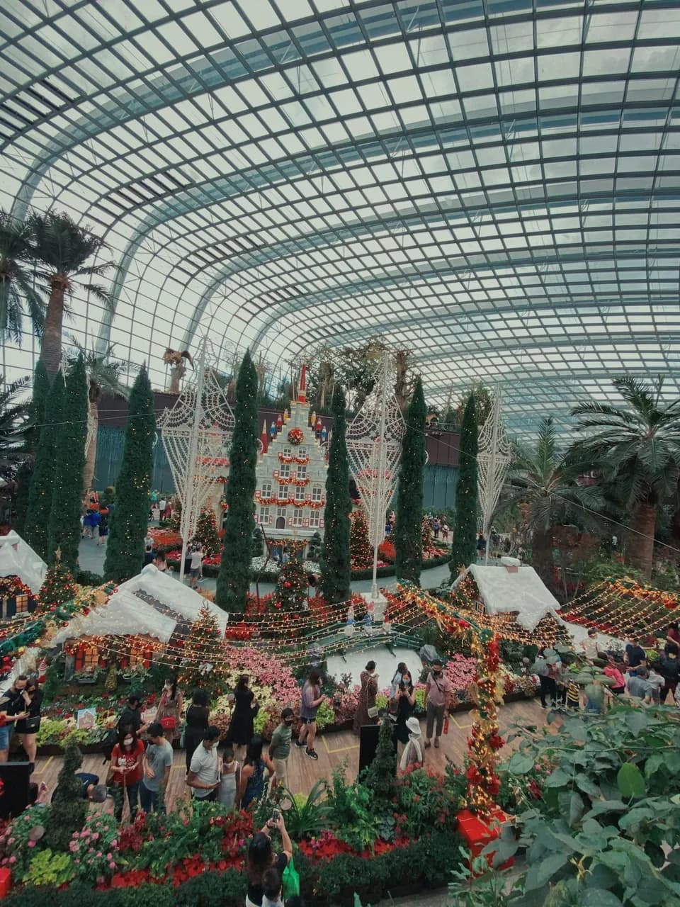 Une grande serre vitrée parée d’un décor de Noël, où se pressent les invités.